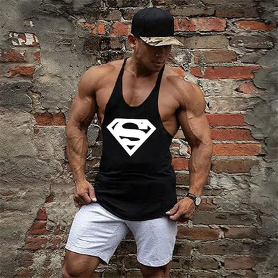 Muscular man wearing men's bodybuilding fitness apparel with a Superman logo against a brick wall.